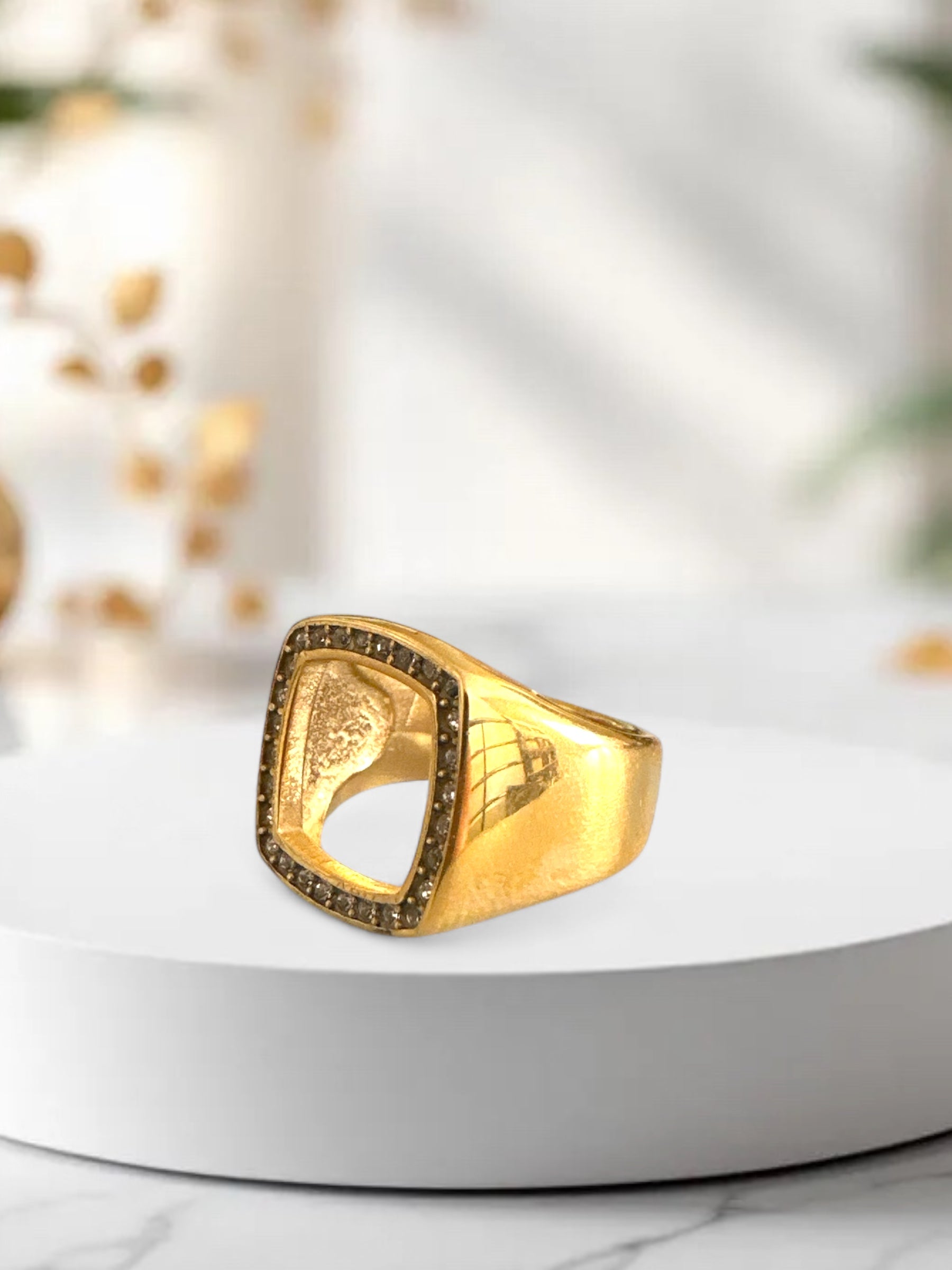 Χρυσό ατσάλινο δαχτυλίδι με λευκά ζιργκόν και γεωμετρικό άνοιγμα, σε μαρμάρινο φόντο.