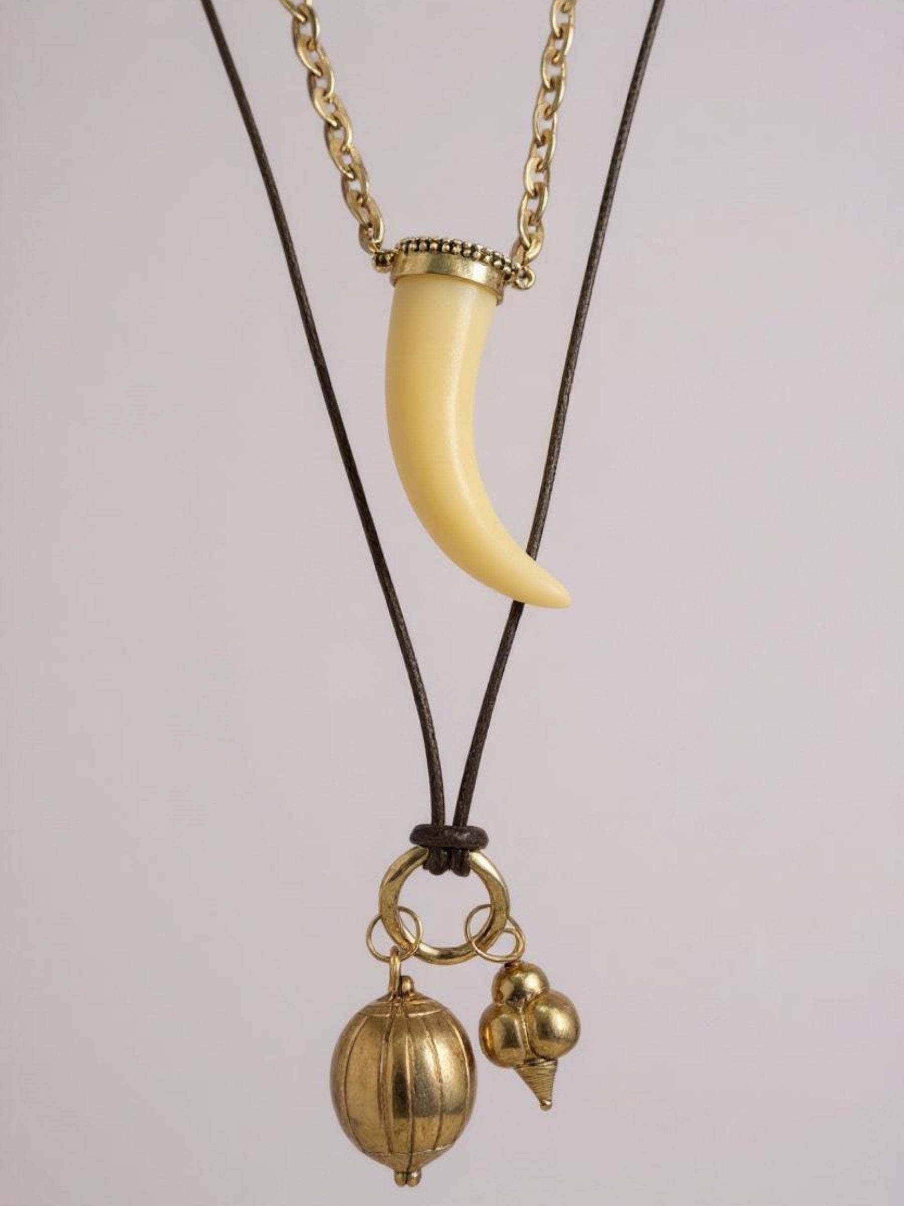 Σετ δύο boho κολιέ So Cute By Dimi: ένα με ακρυλικό δόντι σε χρυσή αλυσίδα και ένα πολύ μακρύ κορδόνι με χρυσά μεταλλικά στοιχεία.