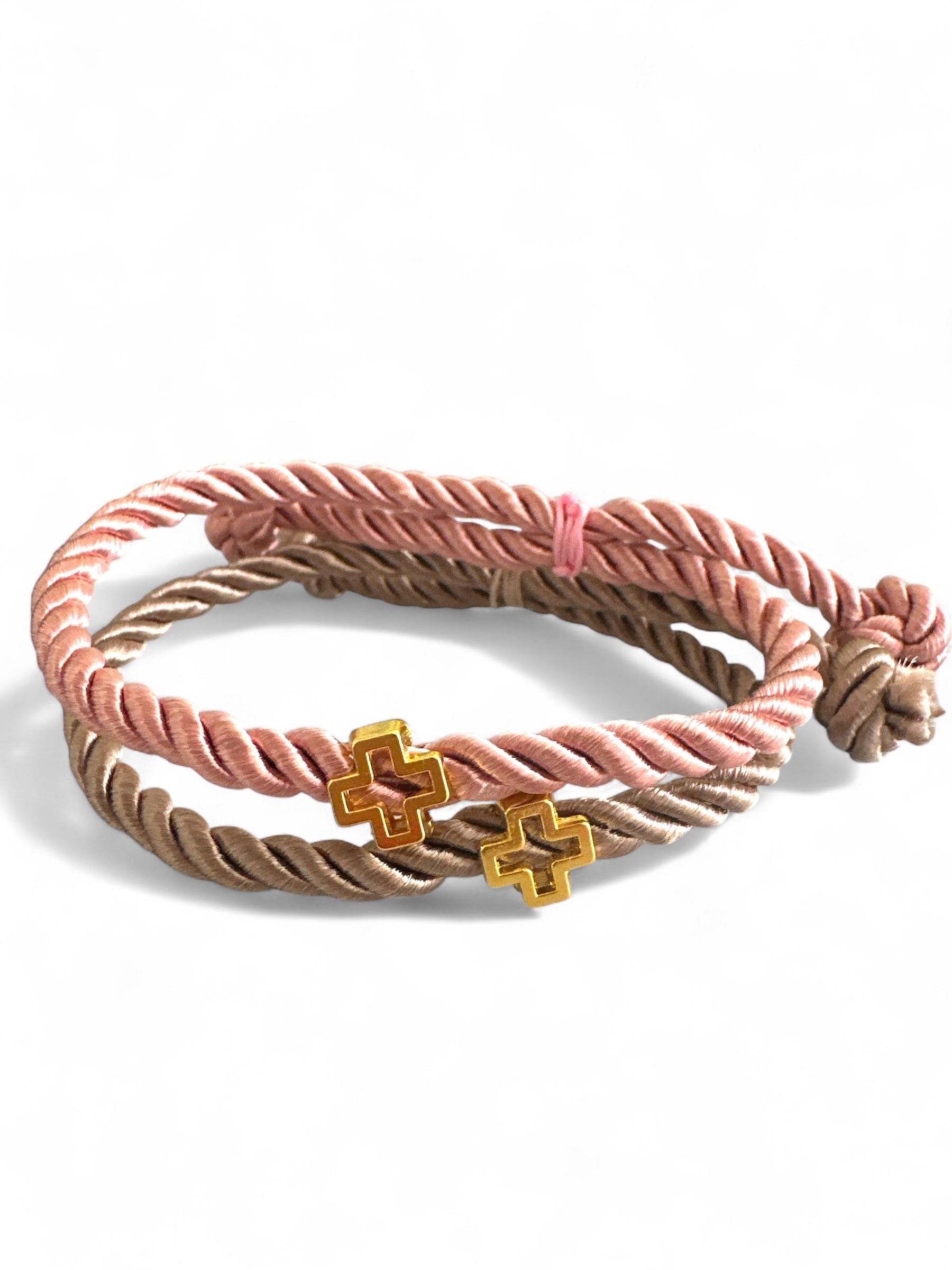 Γυναικείος καρπός με χειροποίητα μαρτυρικά βραχιόλια από στριφτό σατέν κορδόνι και χρυσό σταυρουδάκι – σε dusty pink & μπεζ αποχρώσεις.