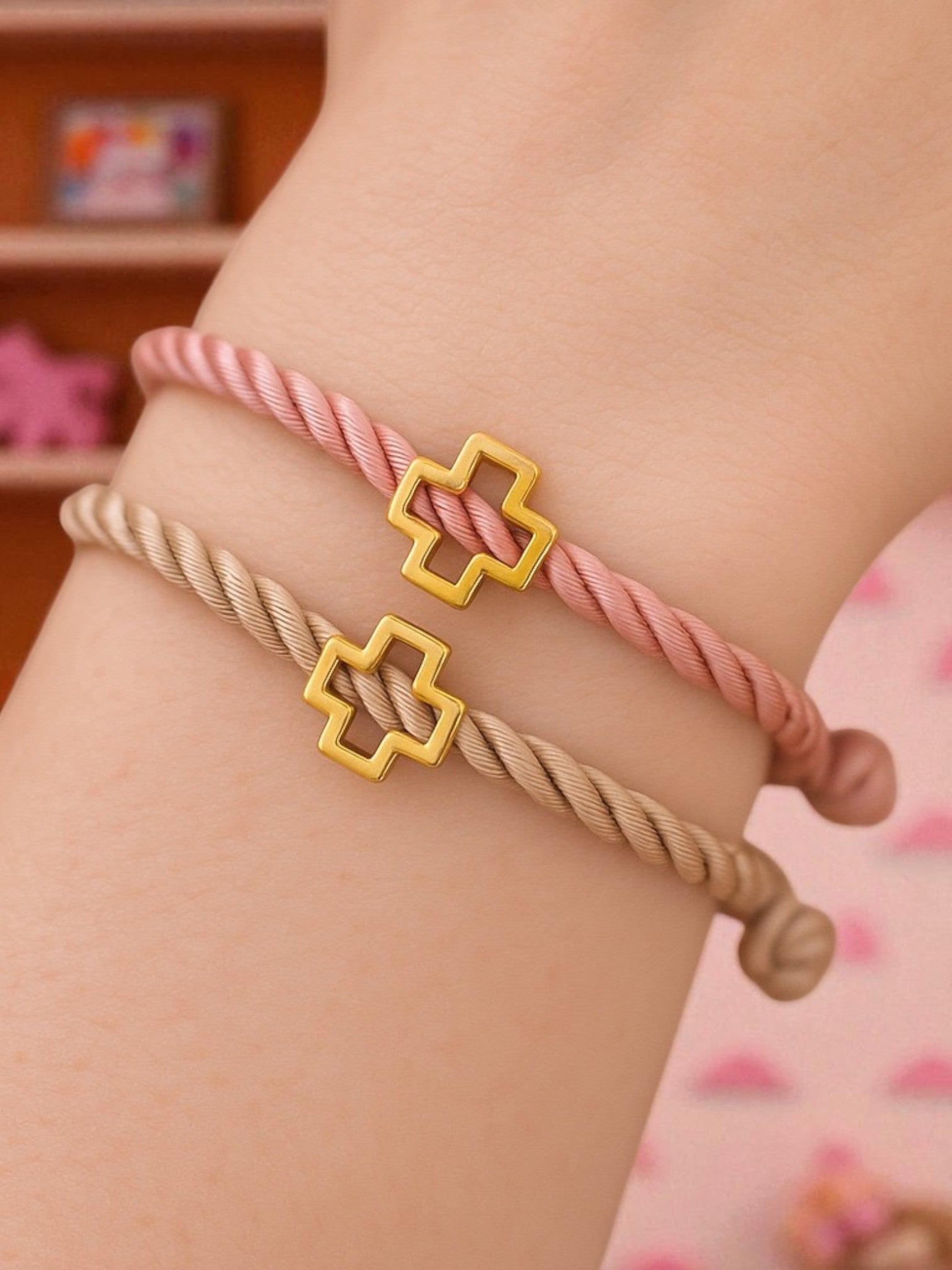 Γυναικείος καρπός με χειροποίητα μαρτυρικά βραχιόλια από στριφτό σατέν κορδόνι και χρυσό σταυρουδάκι – σε dusty pink & μπεζ αποχρώσεις.