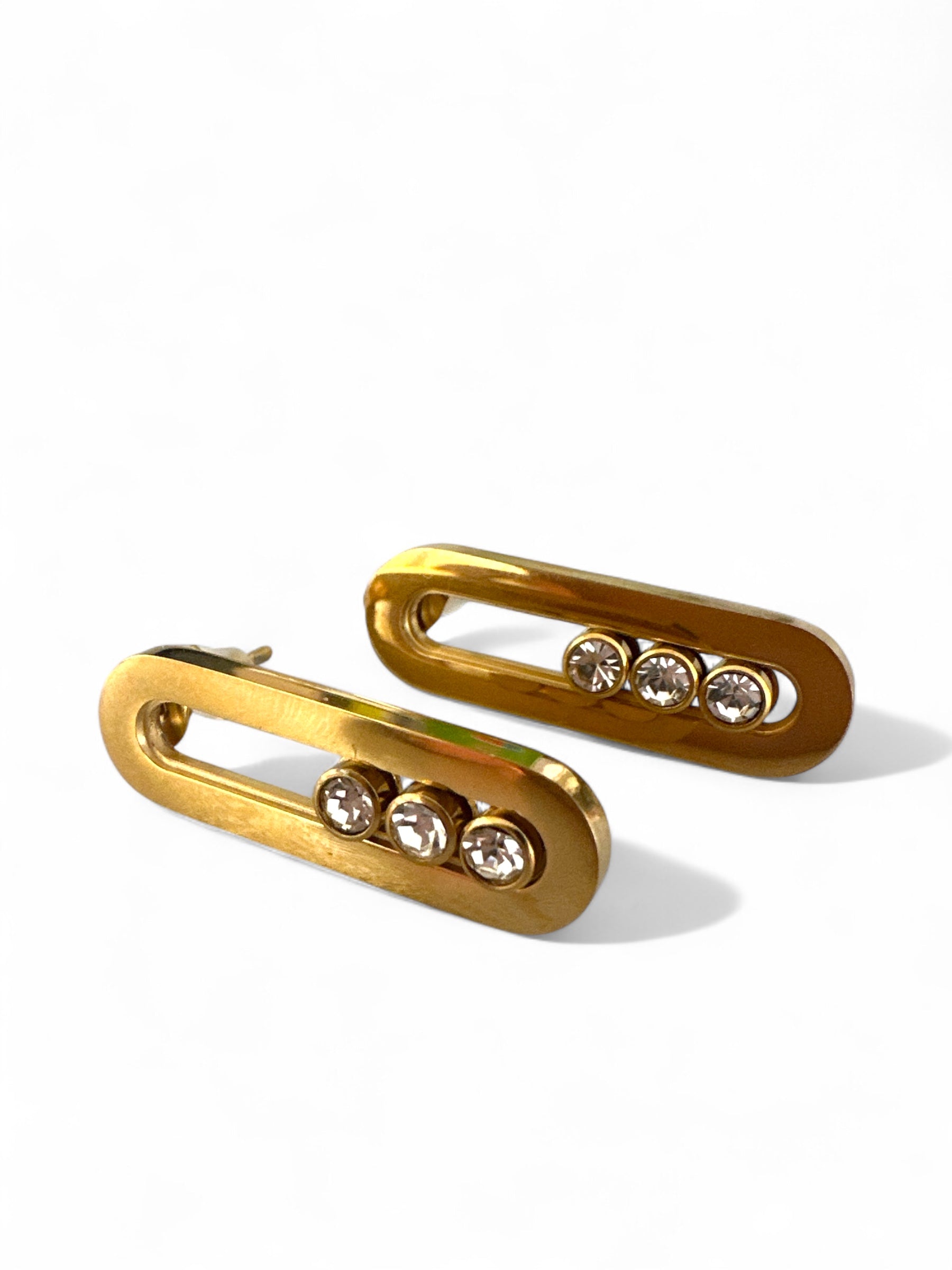 Ατσάλινα σκουλαρίκια σε σχήμα κάθετου οβάλ με τριπλό ζιργκόν, σε χρυσό χρώμα. So Cute by Dimi