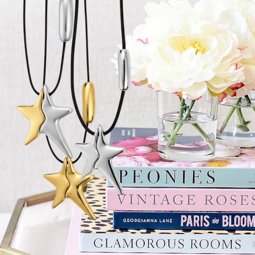 Star-shaped necklaces on a stack of books with flowers in the background- So Cute by DImi