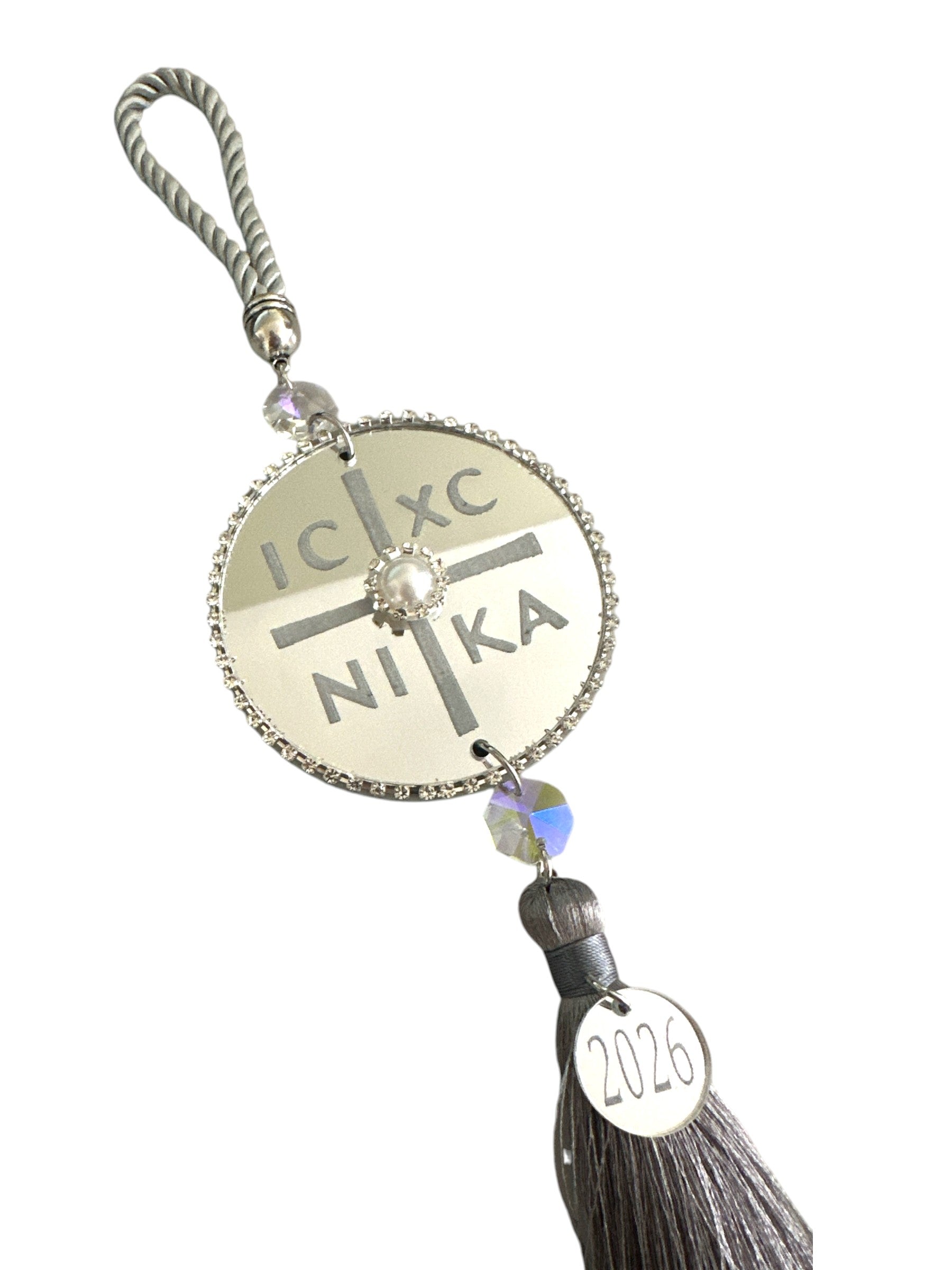 Ασημί IC XC NIKA γούρι σε minimal λευκό flatlay.