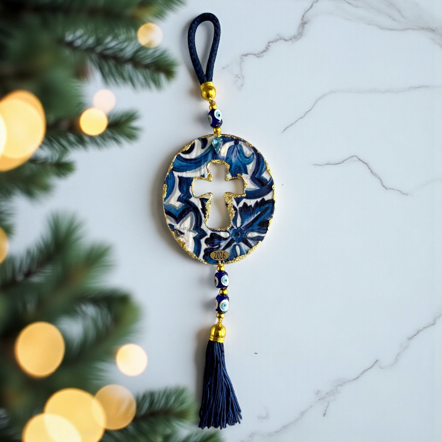 Γούρι 2026 οβάλ σταυρός με μάτια & φούντα – Greek Wishes Λιανική So Cute by Dimi