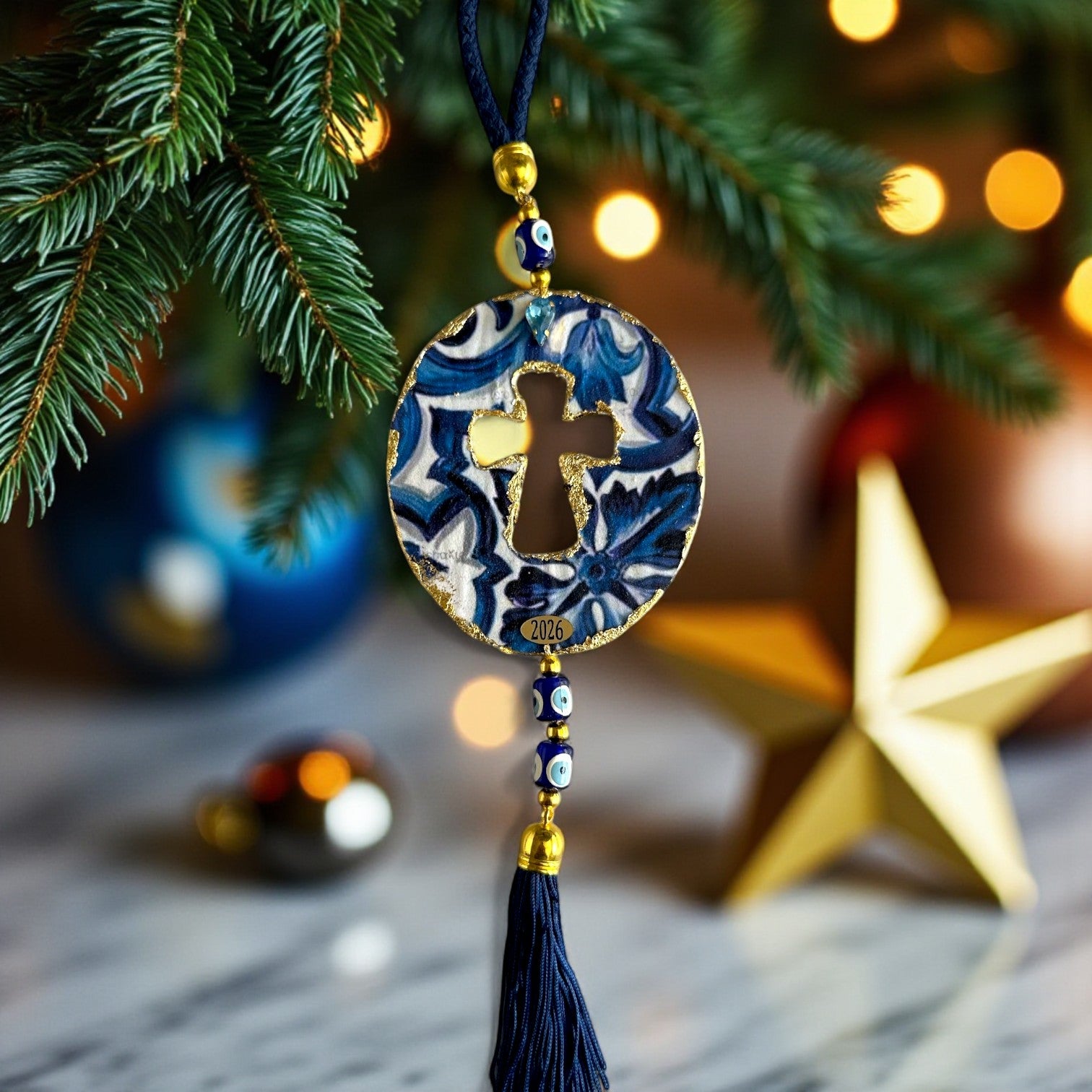 Γούρι 2026 οβάλ σταυρός με μάτια & φούντα – Greek Wishes Λιανική So Cute by Dimi