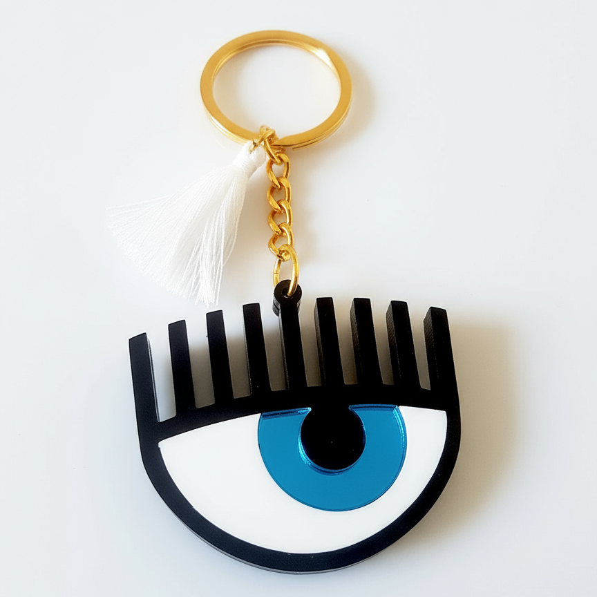 Plexiglass μπρελόκ μάτι με βλέφαρα και φουντίτσα σε μπλε ή χρυσό χρώμα – So Cute by Dimi