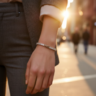 Close-up of a person's hand wearing a bracelet with a blurred city street background