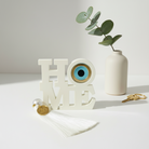 Επιτραπέζιο γούρι HOME με μάτι από πλεξιγκλάς και φούντα σε λευκό χρώμα– So Cute by Dimi