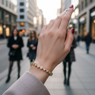 Hand wearing a gold bracelet with blurred city street background