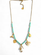 Necklace with turquoise beads and gold charms on a white background So Cute by DImi