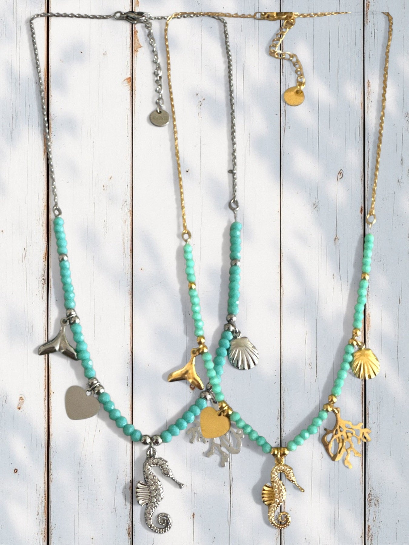 Two necklaces with turquoise beads and various charms on a wooden background So Cute by DImi