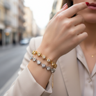 Close-up of a person's hand wearing two bracelets with a blurred city street background