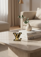 Μικρό διακοσμητικό LV από plexiglass καθρέφτη πάνω σε λευκό μαρμάρινο τραπέζι, δίπλα σε ουδέτερα βάζα.