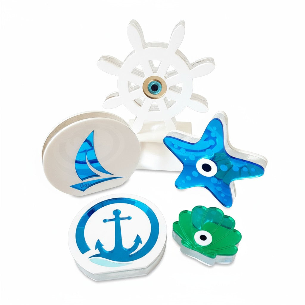 Χειροποίητα ναυτικά γούρια από πλεξιγκλάς σε λευκό φόντο — τιμόνι, άγκυρα, ιστιοφόρο, αστερίας και κοχύλι σε μπλε, λευκές και γαλάζιες αποχρώσεις, So Cute by Dimi.