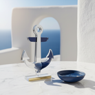 Επιτραπέζιο γούρι άγκυρα από ασημί και μπλε πλεξιγκλάς καθρέφτη σε minimal κυκλαδίτικο σκηνικό με λευκό μάρμαρο, γαλάζιες λεπτομέρειες και φυσικό μεσογειακό φως, So Cute by Dimi.