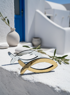 Χρυσό και ασημί επιτραπέζιο ψάρι από πλεξιγκλάς σε κυκλαδίτικο σκηνικό πάνω σε λευκή επιφάνεια